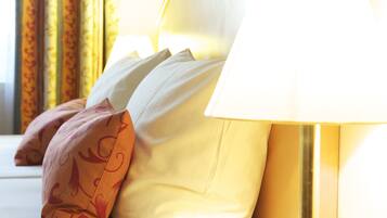A bed with white and patterned pillows, a bedside lamp, and curtains with a floral pattern.