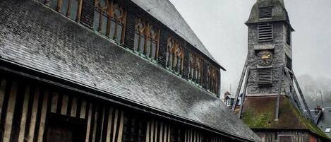 A historic building with a steeply pitched roof and a prominent tower with a clock.