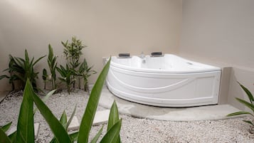 A spa area with a white hot tub surrounded by gravel and potted plants.