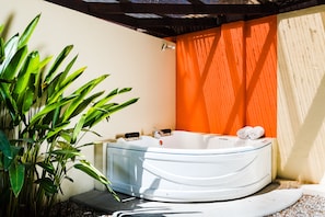 A hot tub with a glass enclosure, surrounded by plants and a tiled floor.