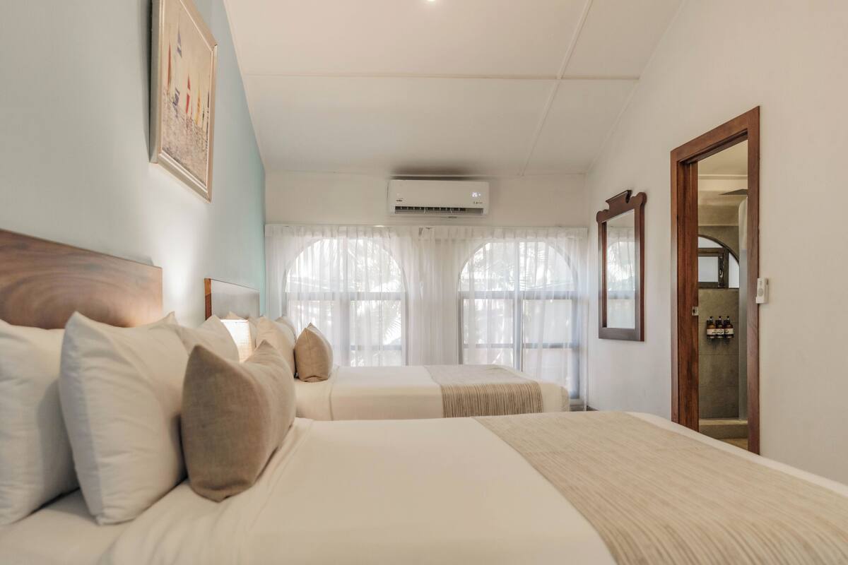 Une chambre d’hôtel avec deux lits, un grand miroir et un appareil de climatisation.