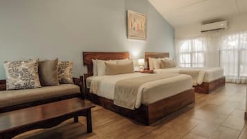 A bedroom with two beds, a sofa, a wooden bench, and a painting on the wall.