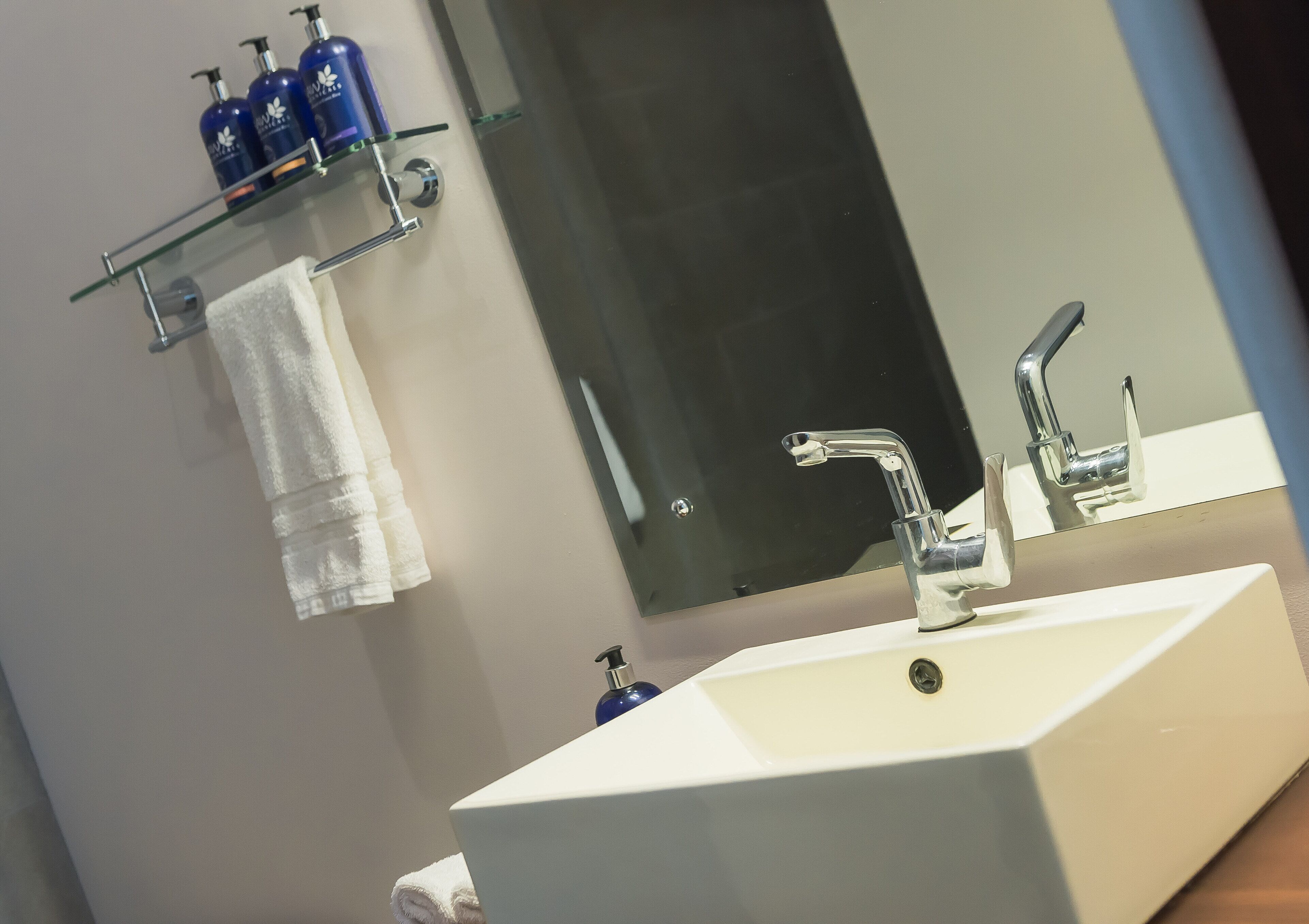 A bathroom with a white sink, a mirror, and a towel hanging on a rack.