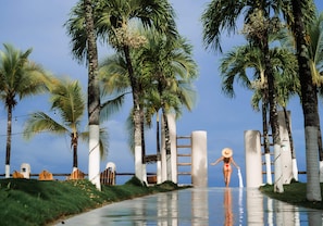 A pathway lined with palm trees and a person in a bikini.