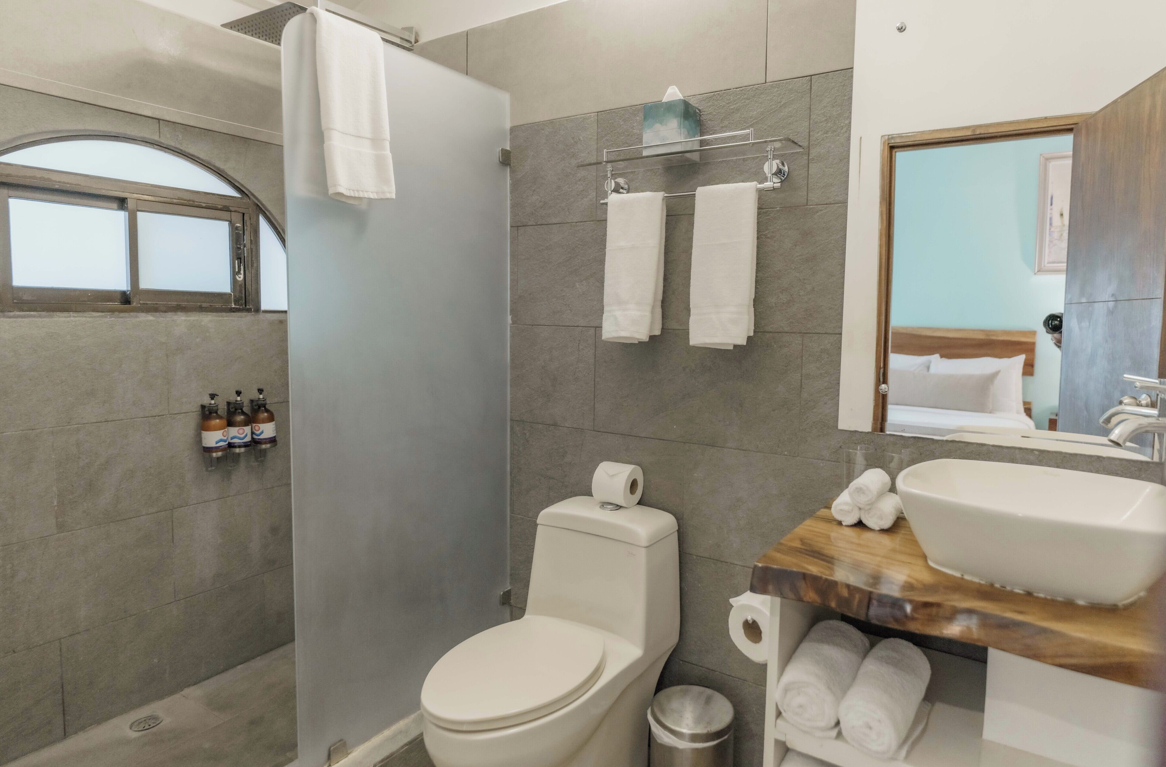 Ein modernes Badezimmer mit Dusche, Toilette und Waschbecken. Handtücher und Pflegeprodukte sind sichtbar.