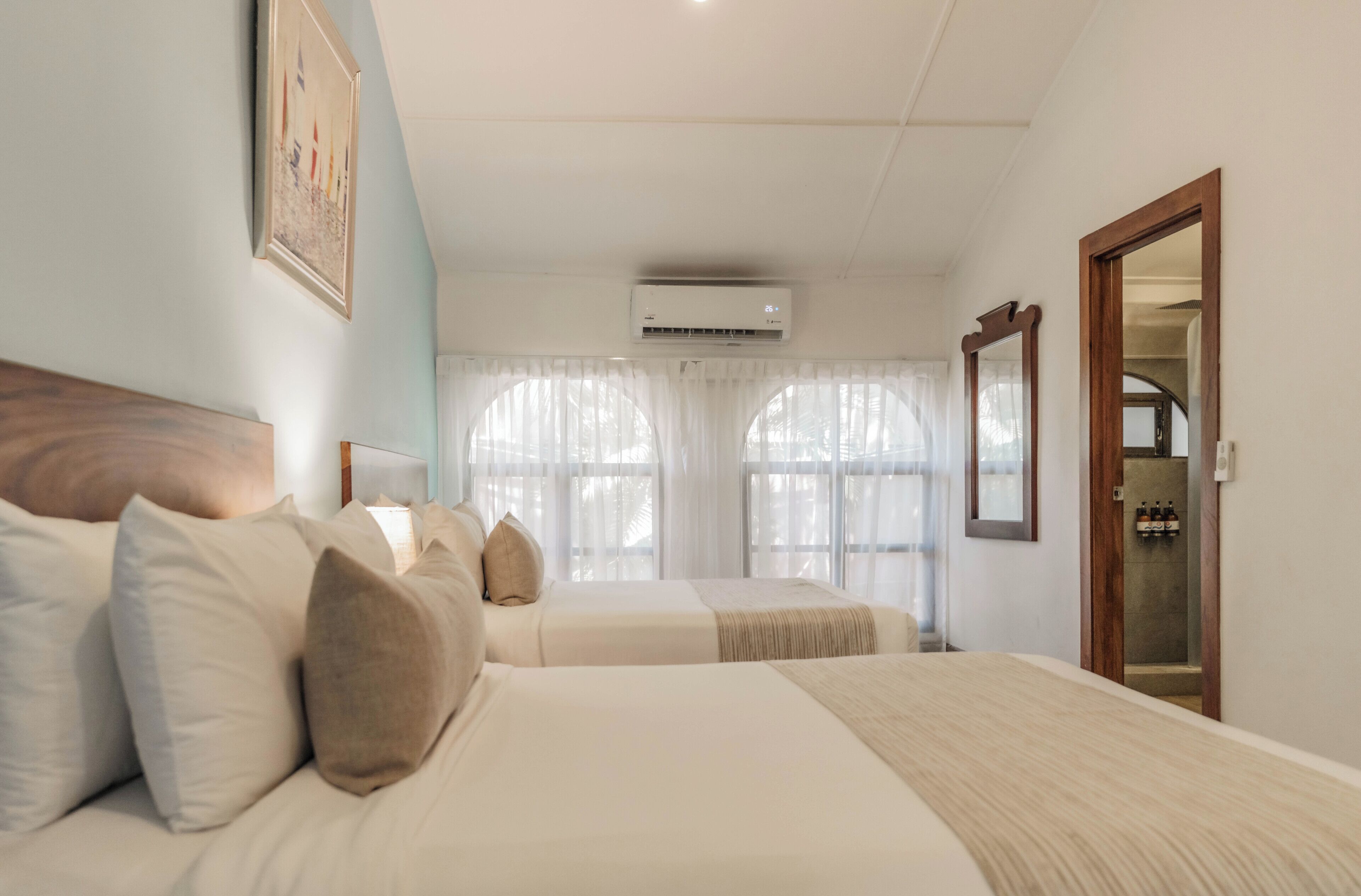 Ein Hotelzimmer mit zwei Betten, einem großen Spiegel und einer Klimaanlage.