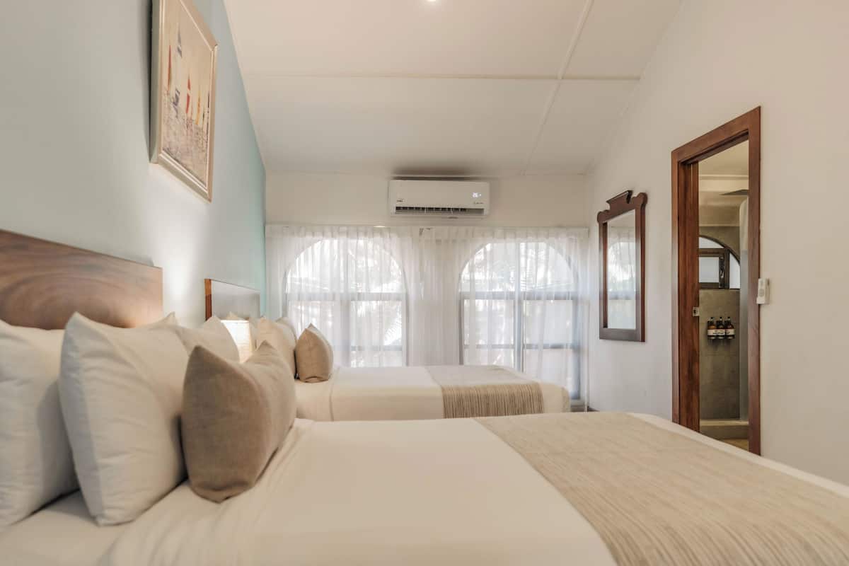 Une chambre d’hôtel avec deux lits, un grand miroir et un appareil de climatisation.
