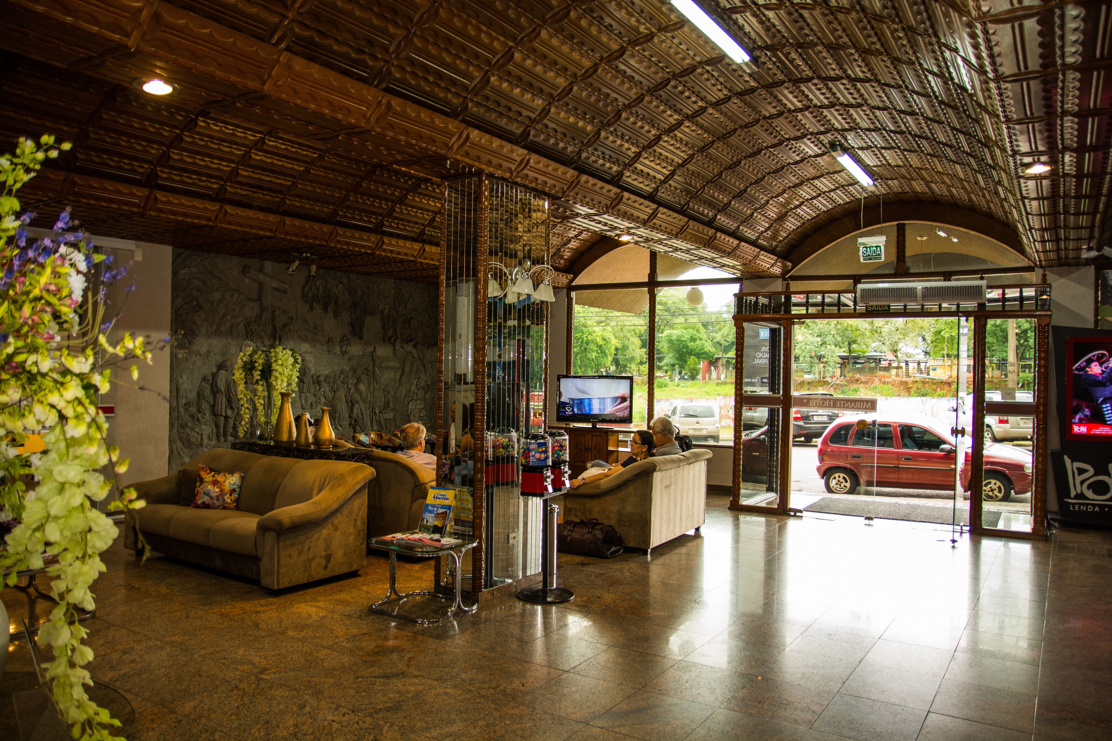A lobby with a high ceiling, a reception desk, seating area, and a view of the outside.