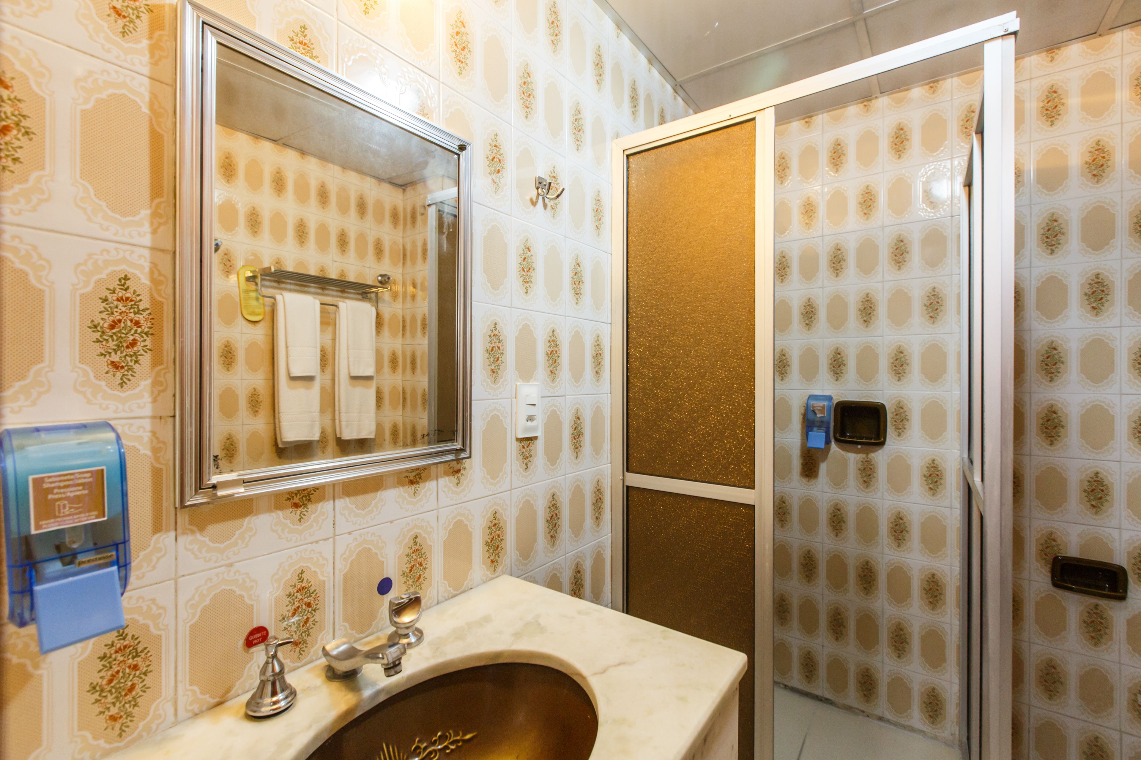 A bathroom with a sink, mirror, and shower area.