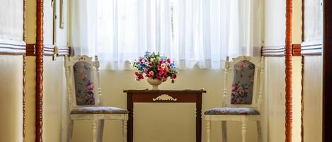 Et værelse med to stole og et bord med blomsterarrangement.