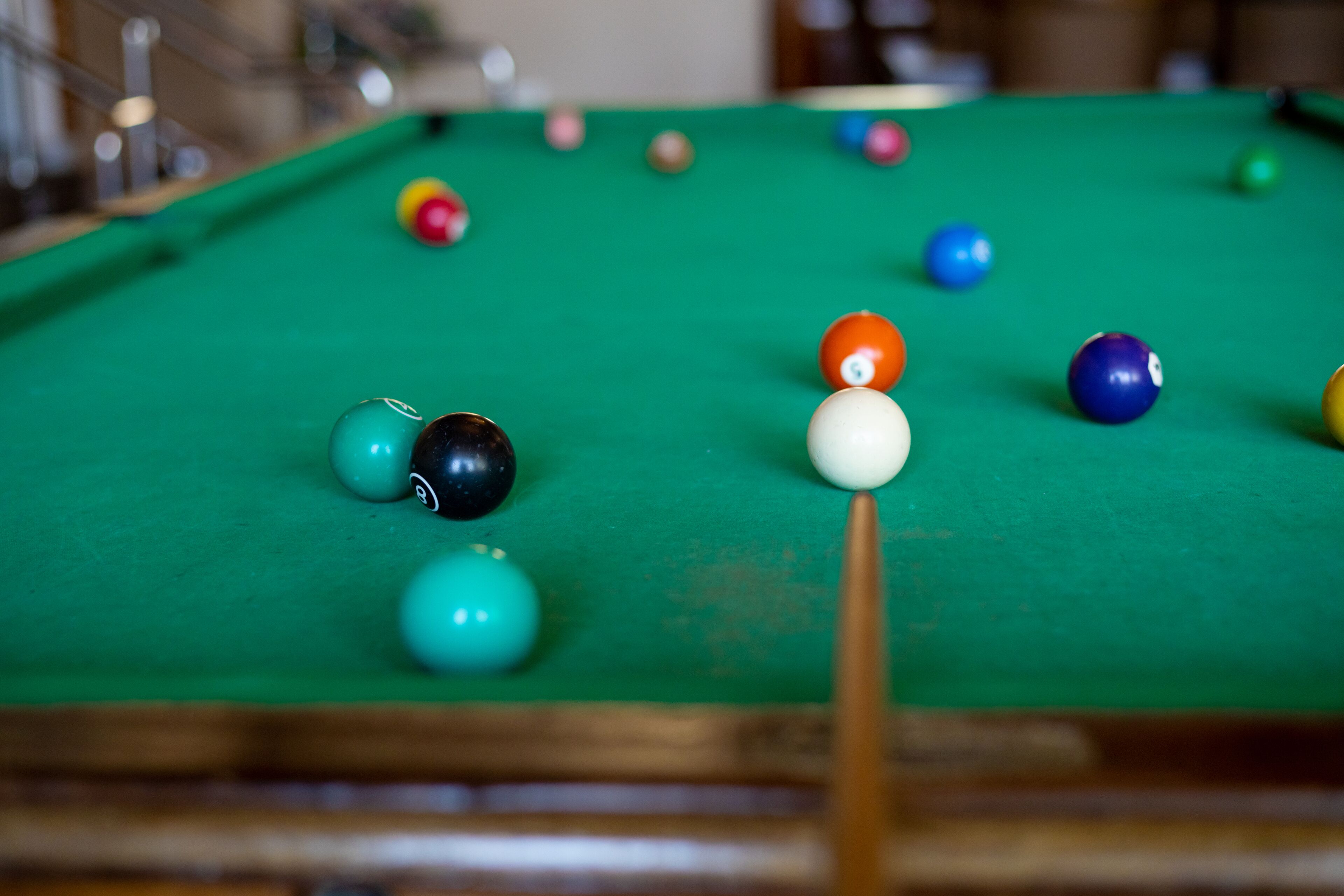 A pool table with various colored balls and a pool cue.
