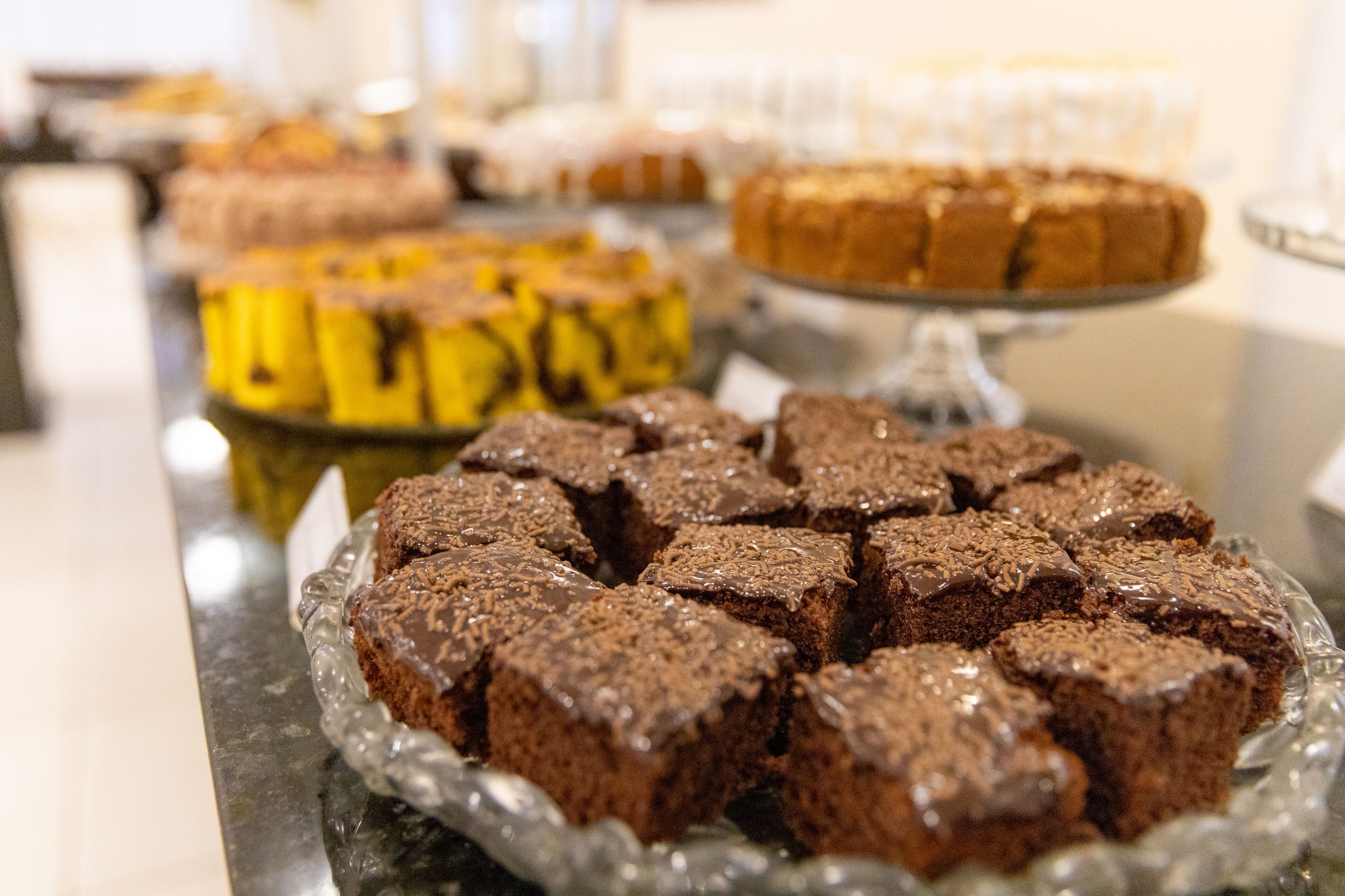A buffet table with various desserts including brownies and a cake.