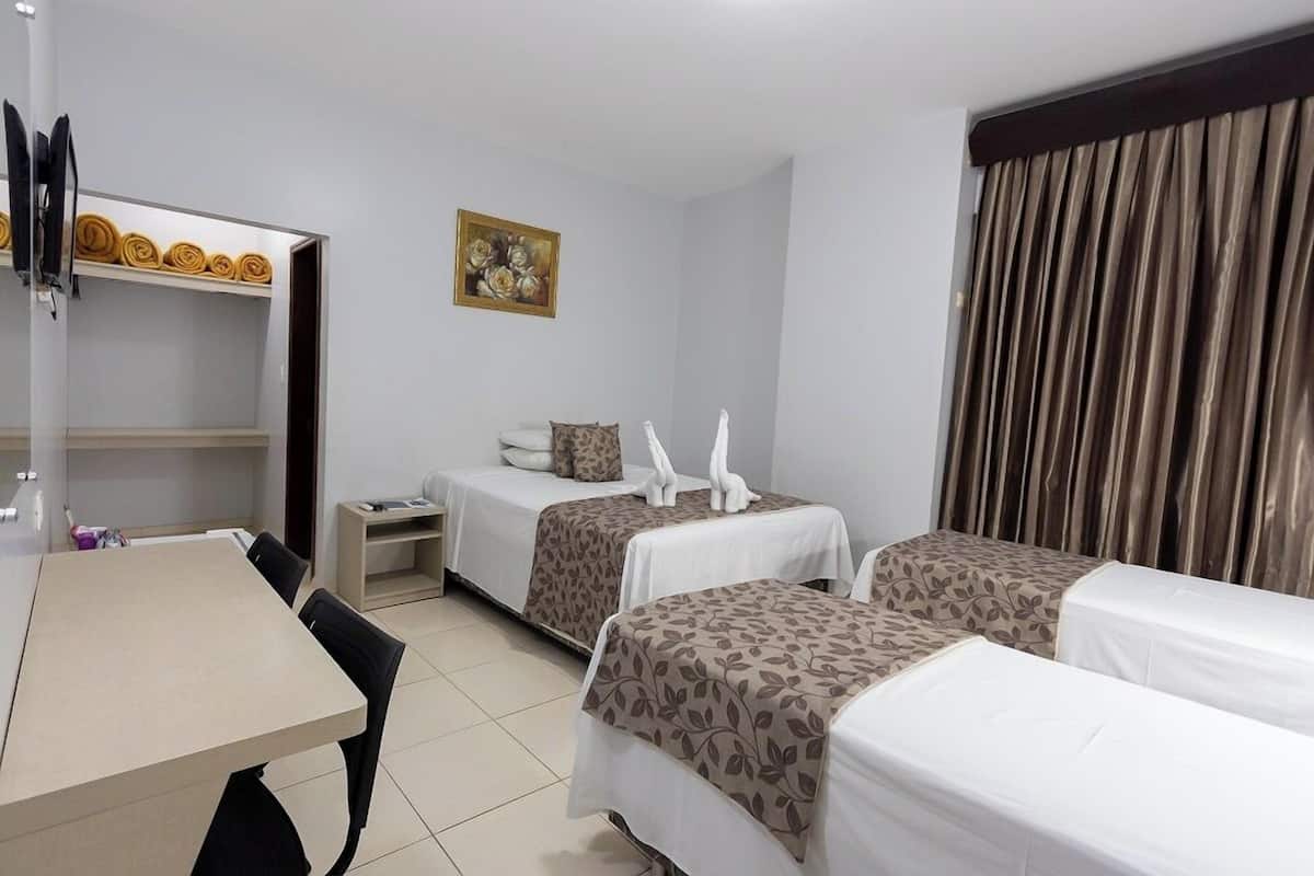 Een hotelkamer met twee bedden, een bureau en een stoel. Er hangt een schilderij aan de muur en er is een gordijn voor het raam.