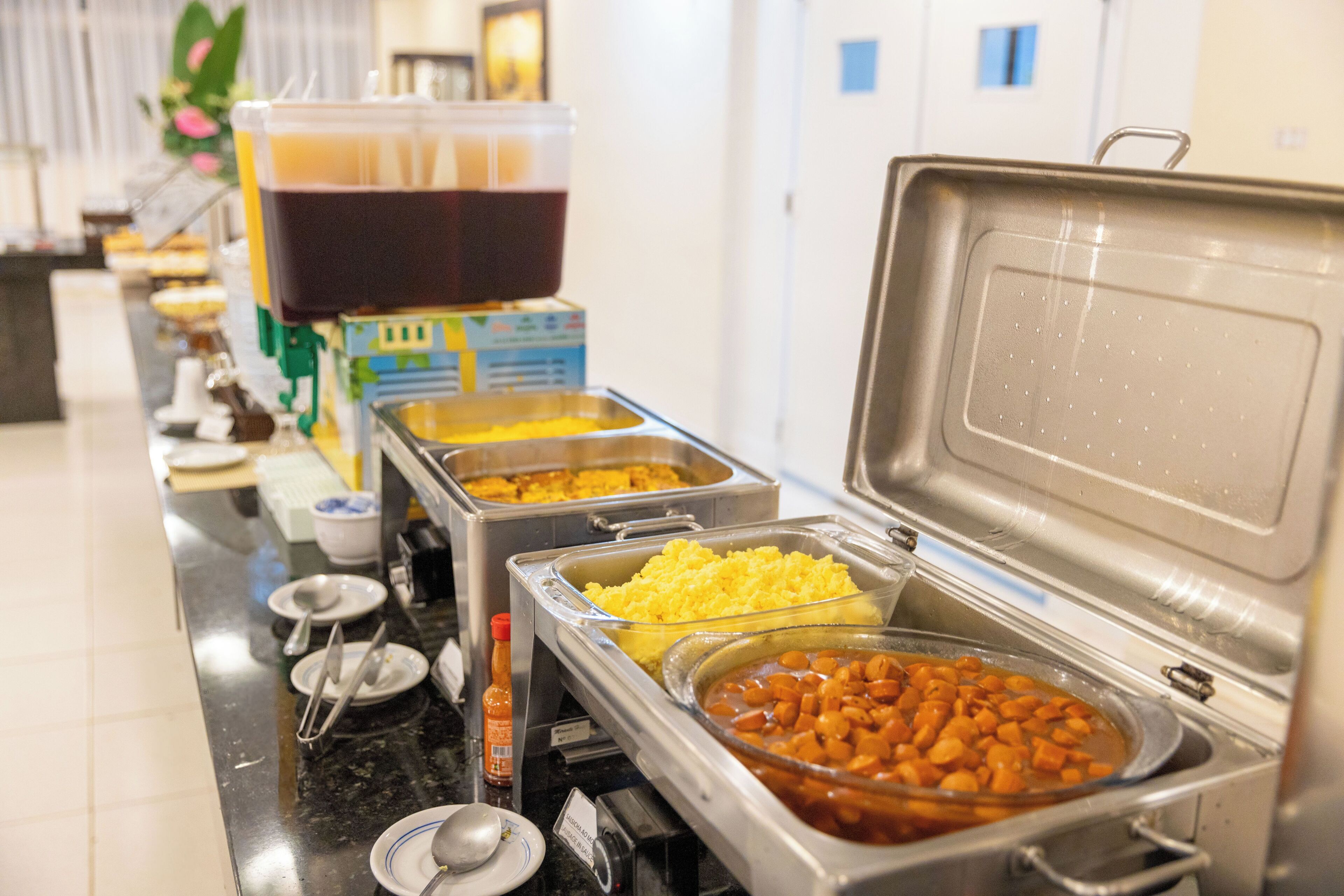 A buffet with various food options including a container of beans, a bowl of rice, and a container of soup.