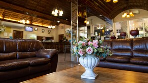A cozy interior with leather sofas, a wooden table, and a vase of flowers.