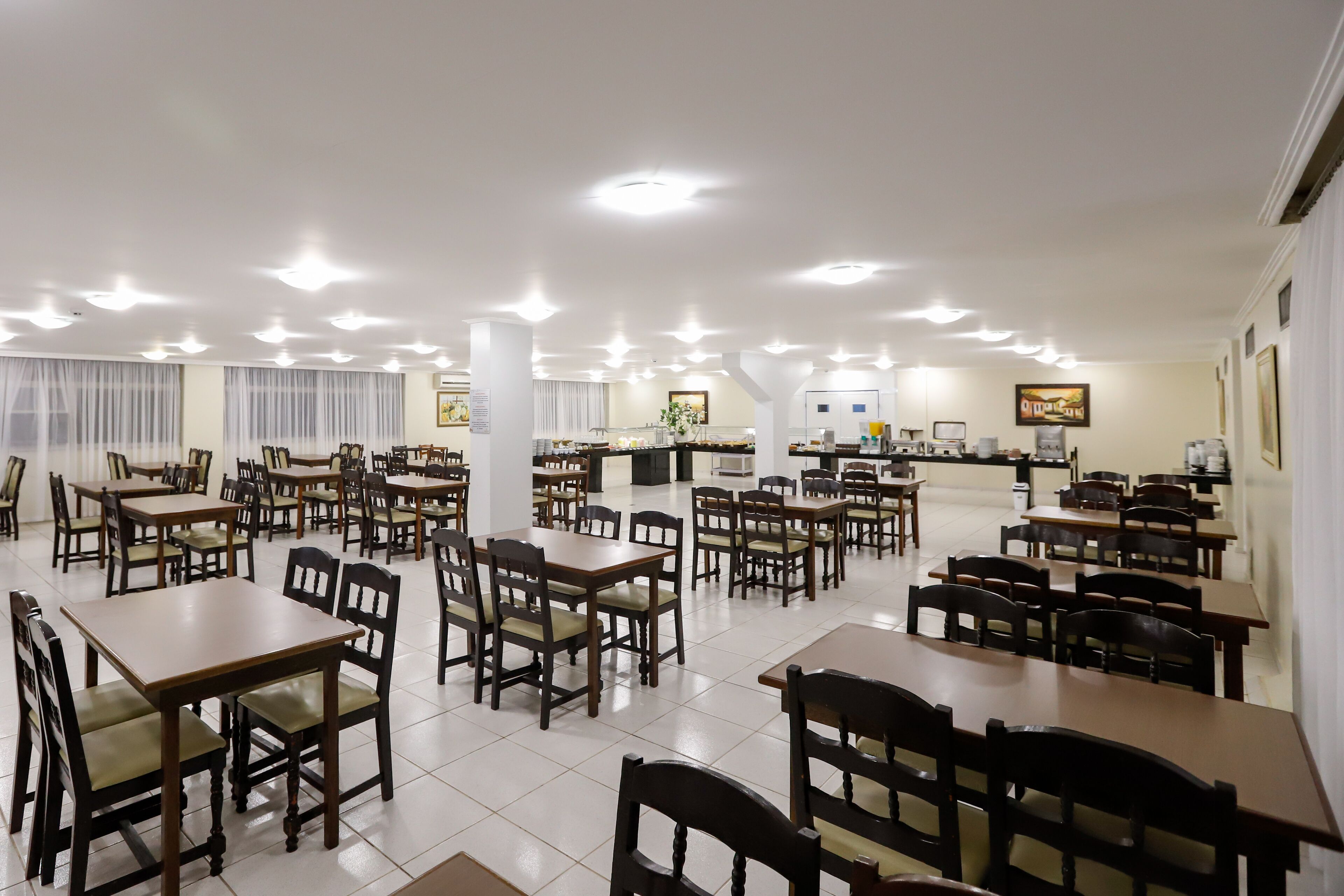Un grand espace dédié à la salle à manger, avec plusieurs tables et chaises, un comptoir avec une caisse enregistreuse et un téléviseur fixé au mur.