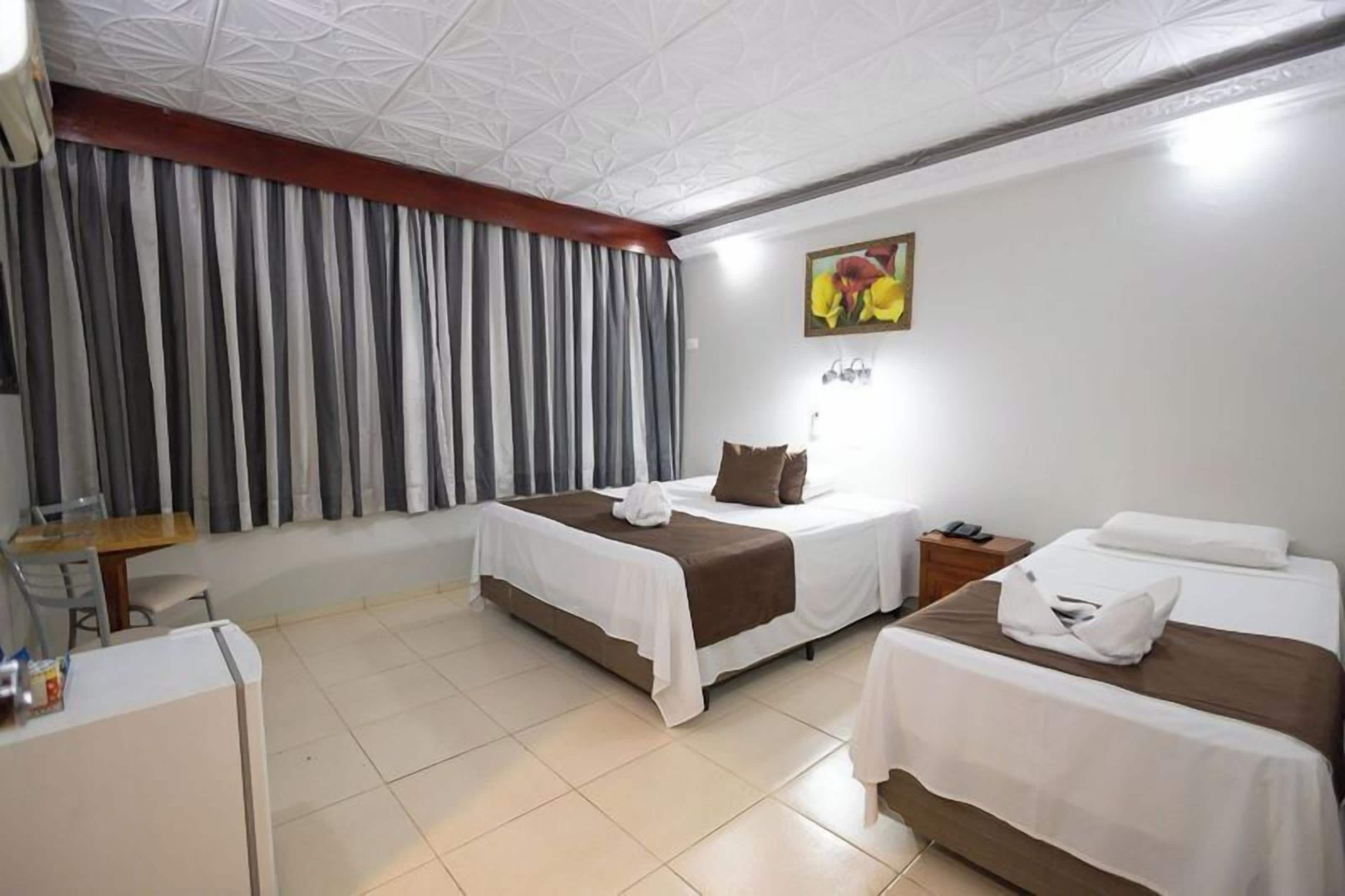 A hotel room with two beds, a desk, and a chair.