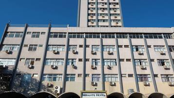 Um edifício de vários andares com numerosas janelas e aparelhos de ar condicionado. O edifício tem uma placa com a inscrição
