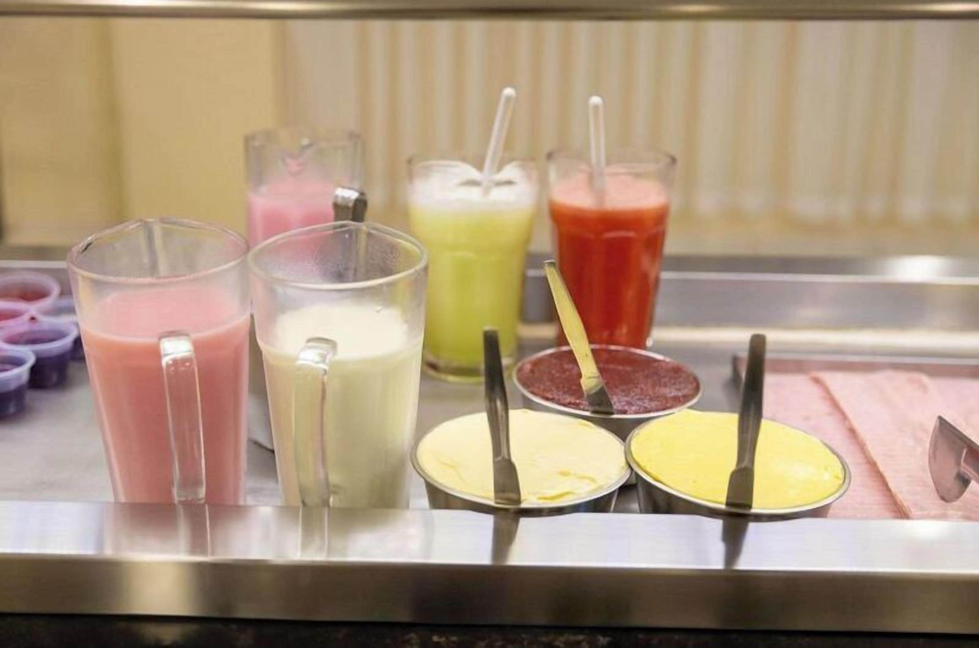 A beverage station with various drinks in glasses and containers.