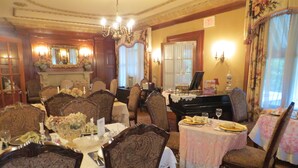 A formal dining room with ornate furniture, a grand piano, and a chandelier.