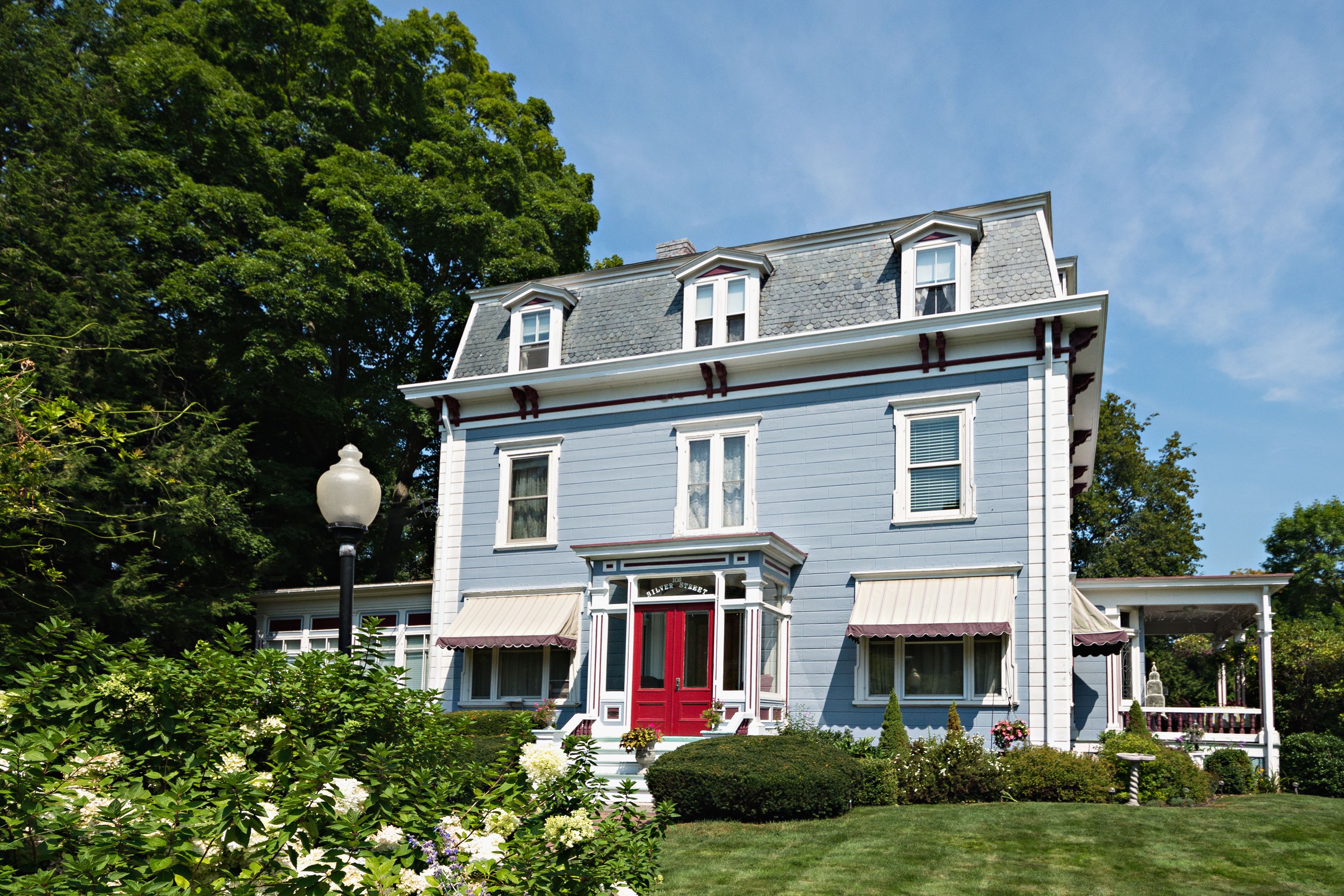 A two-story house with a red front door, white trim, and a porch.