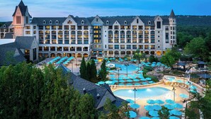A large hotel with multiple floors, a swimming pool, and outdoor umbrellas. - Renaissance Birmingham Ross Bridge Golf Resort & Spa (Birmingham)