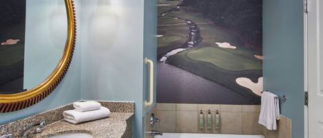 Une salle de bain avec un lavabo, un miroir et une baignoire. On y trouve un porte-serviettes sur lequel est accrochée une serviette.