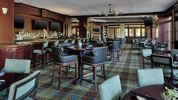 A bar area with a variety of seating options, including bar stools and tables, and a patterned carpet.