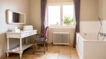 A bathroom with a white vanity, a chair, a radiator, and a bathtub.