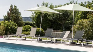 Ein Poolbereich mit Liegestühlen und Sonnenschirmen.