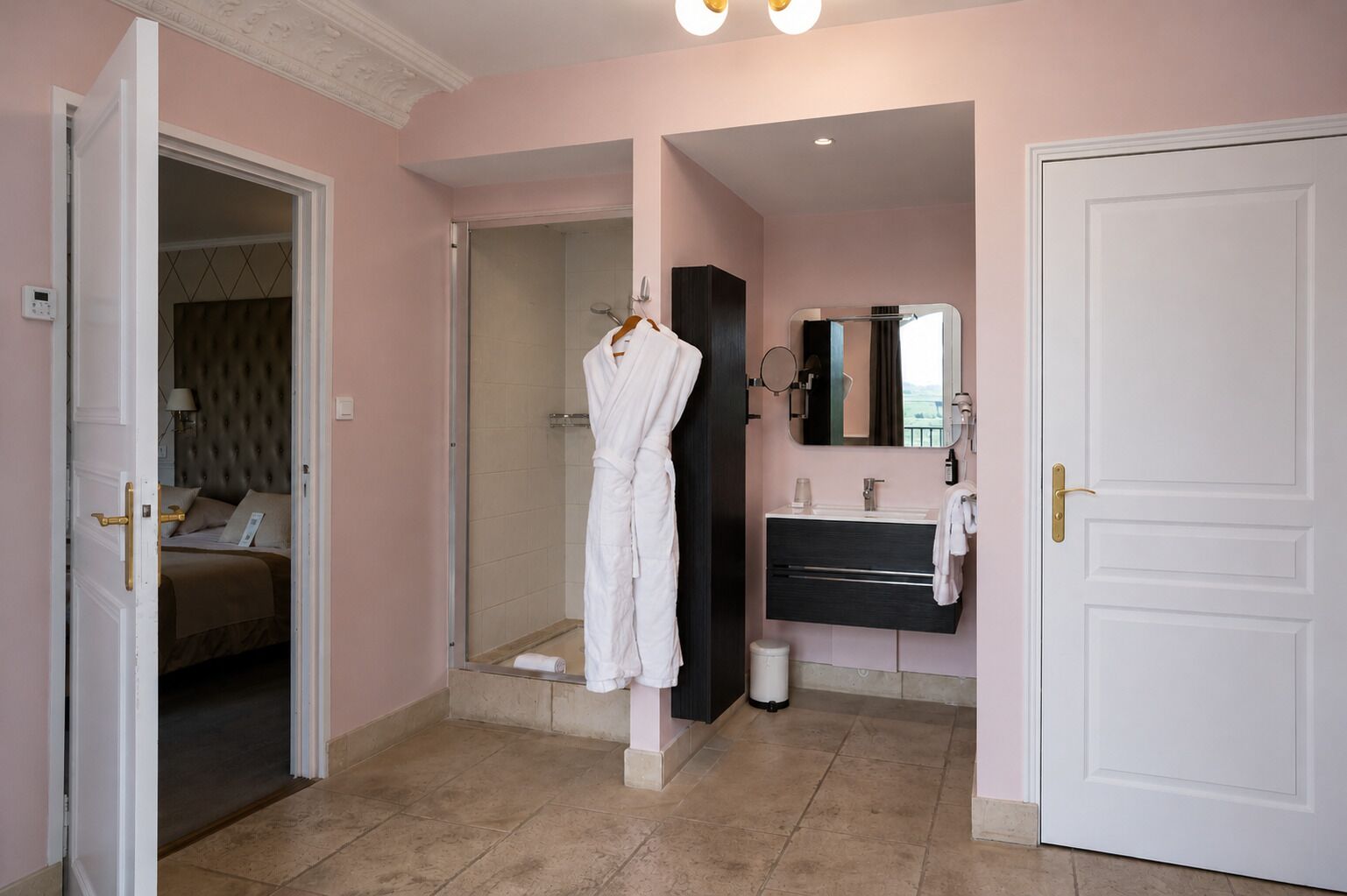 A hotel room with a bed, a bathroom with a mirror, and a door.