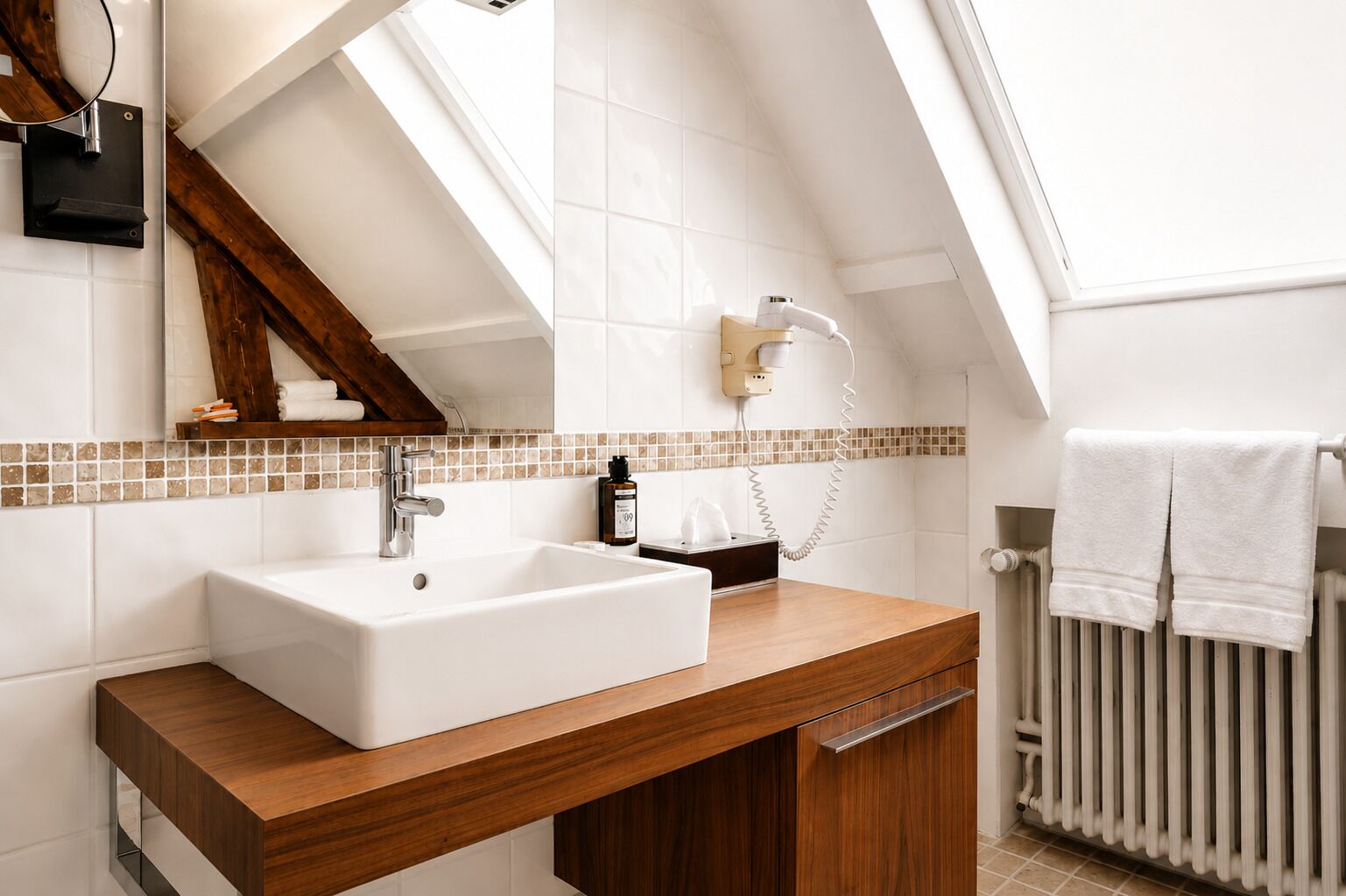 A modern bathroom with a large white sink, wooden vanity, a towel rack, and a visible radiator.