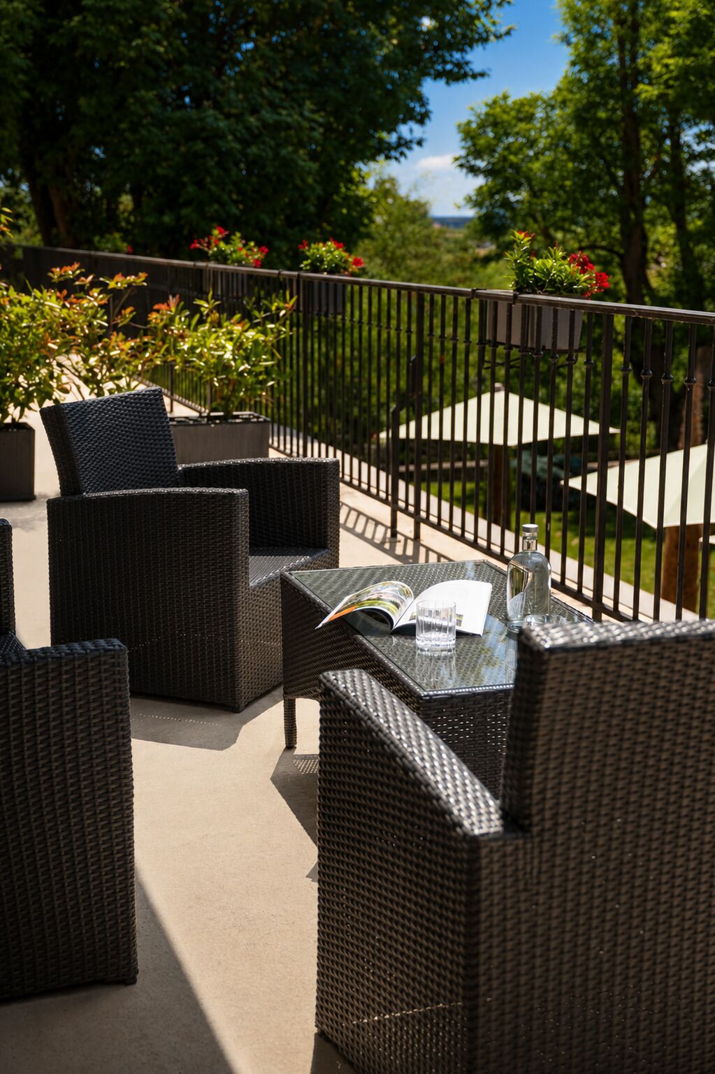 Eine Terrasse im Freien mit Korbmöbeln, einem Glastisch und einem Buch.