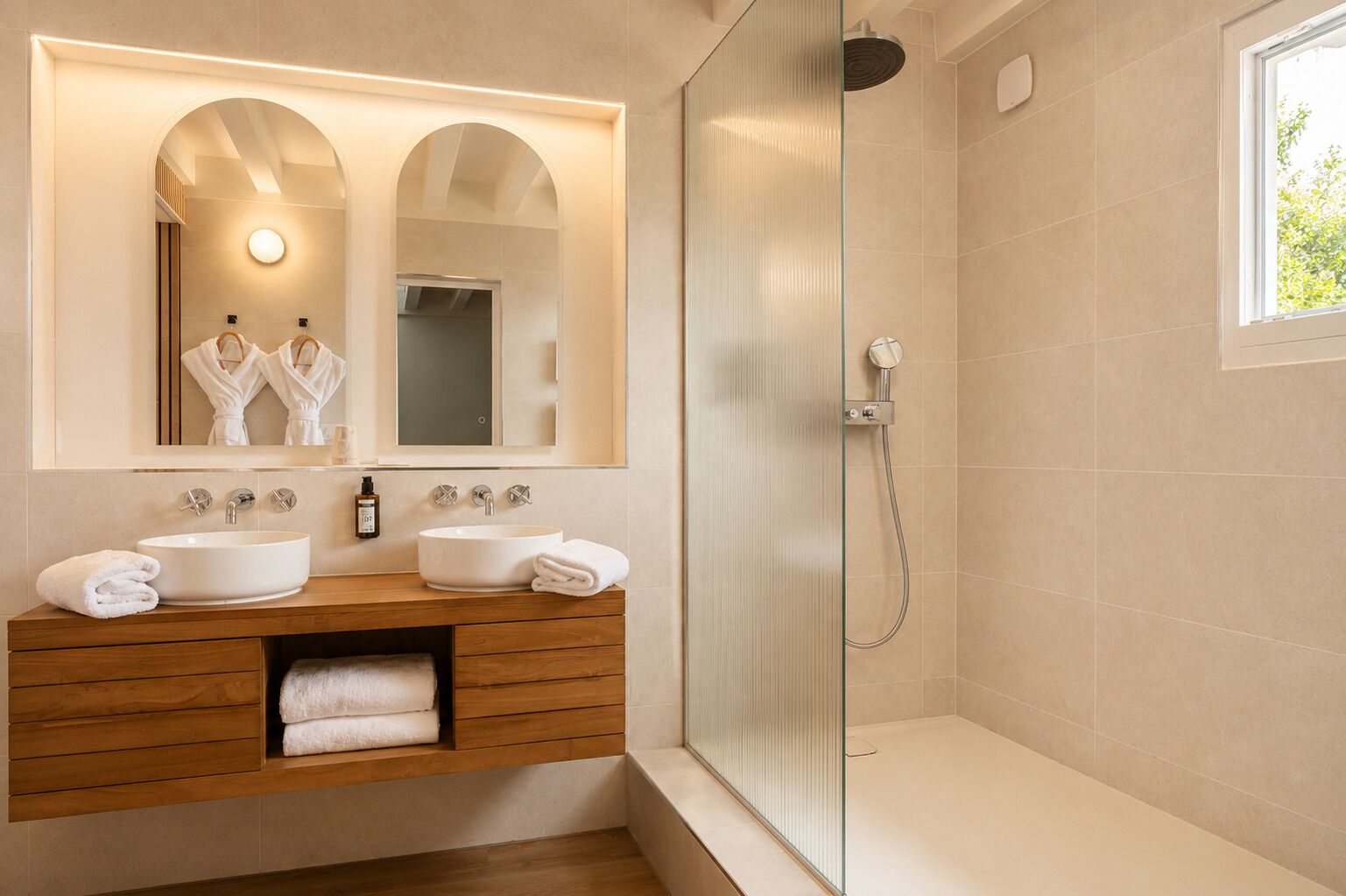 Une salle de bain moderne avec deux lavabos, une douche en verre et un grand miroir avec éclairage intégré.