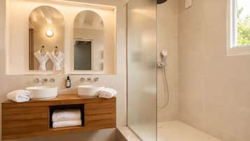 Une salle de bain moderne avec deux lavabos, une douche en verre et un grand miroir avec éclairage intégré.