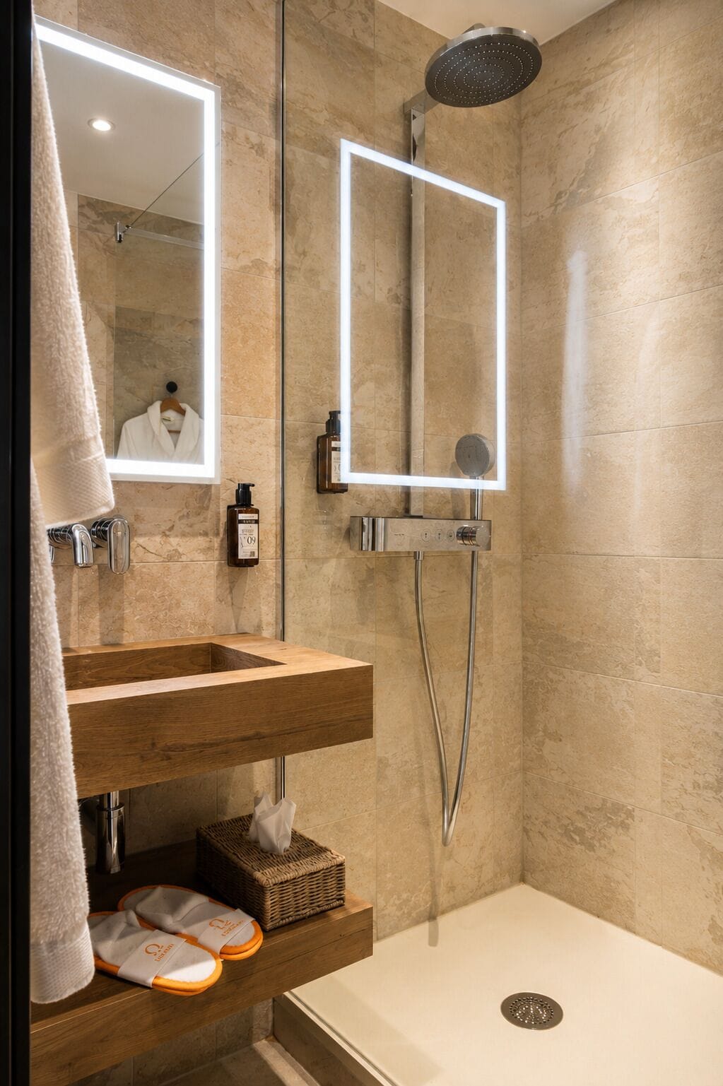 Un baño moderno con tocador de madera, un espejo grande, un cabezal de ducha manual y un box de ducha separado.