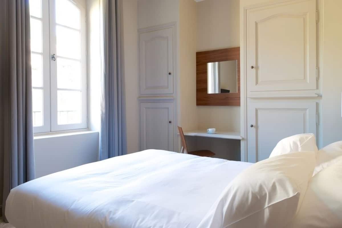 A hotel room with a bed, a desk, and a chair.