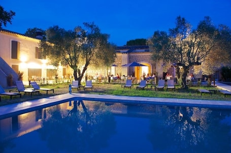 Una piscina al aire libre, sombrillas, sillones reclinables de piscina
