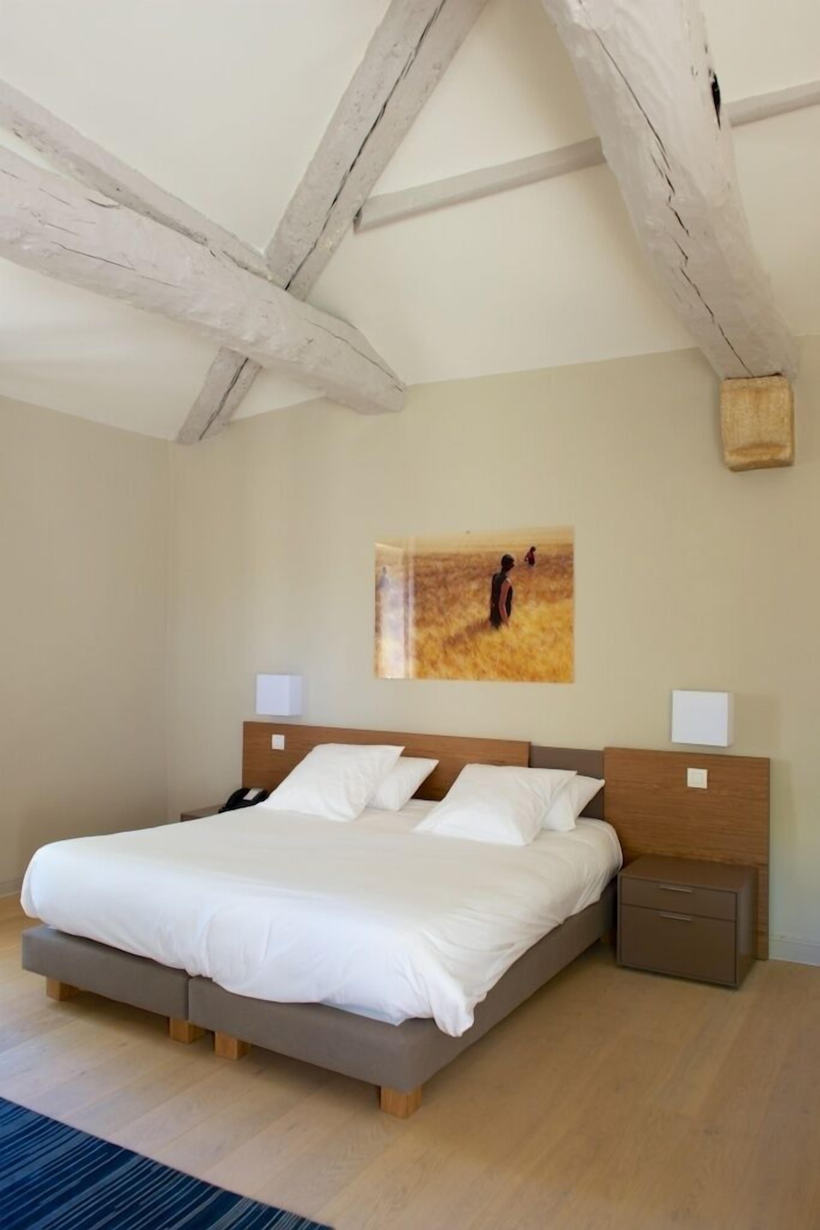 Un dormitorio con una cama grande, cabecera de madera, mesitas de noche y un cuadro en la pared.