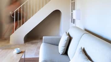Un interior moderno con una escalera, un sofá gris y una mesa de centro de madera.