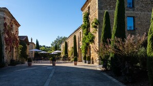 A cobblestone street with stone buildings, outdoor seating, and potted plants. - La Villa Romaine (Carsac-Aillac)