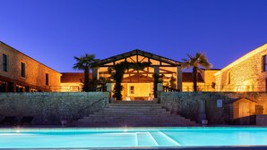 A stone building with a pool in front, featuring a covered patio area and palm trees. - La Villa Romaine (Carsac-Aillac)