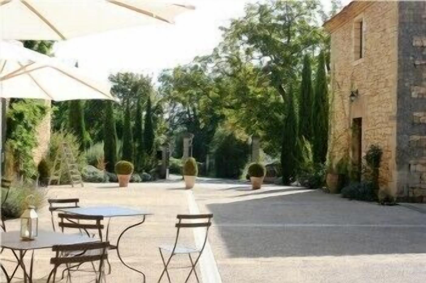 An outdoor patio area with tables and chairs, surrounded by potted plants and trees.