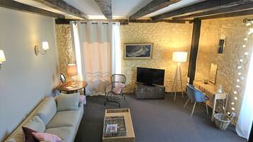 Una sala de estar acogedora con sofá, mesa de centro, televisor, lámpara y pared de piedra.