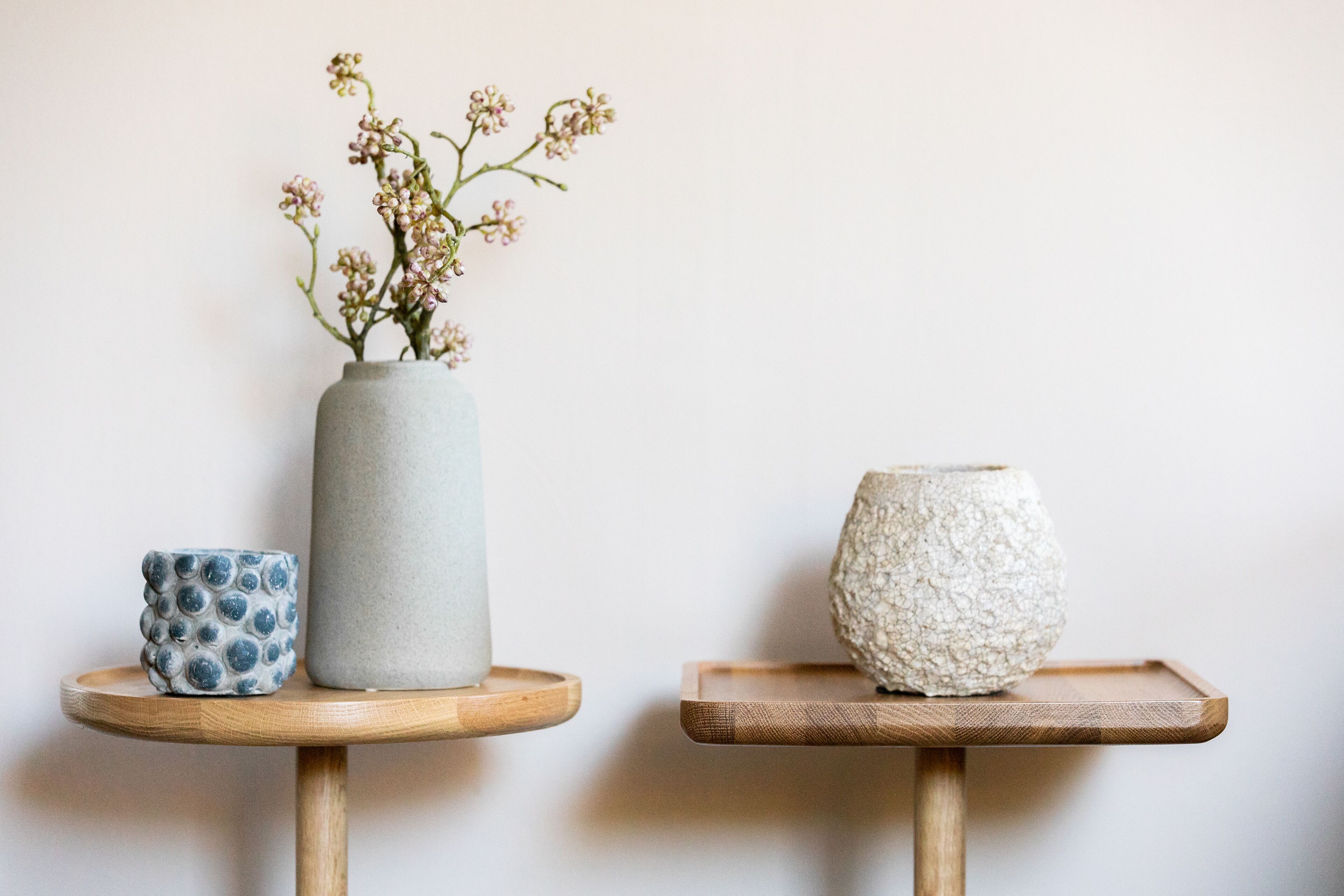 Two small wooden tables with vases on them.