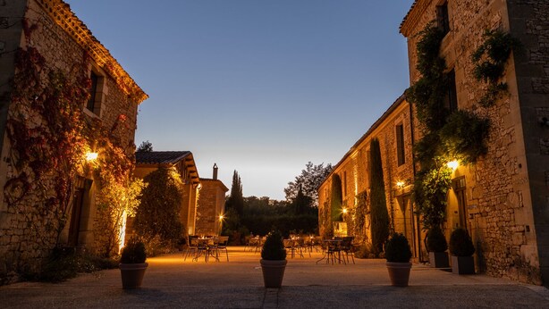 A historic street with stone buildings, outdoor seating, and warm lighting. - La Villa Romaine (Carsac-Aillac)