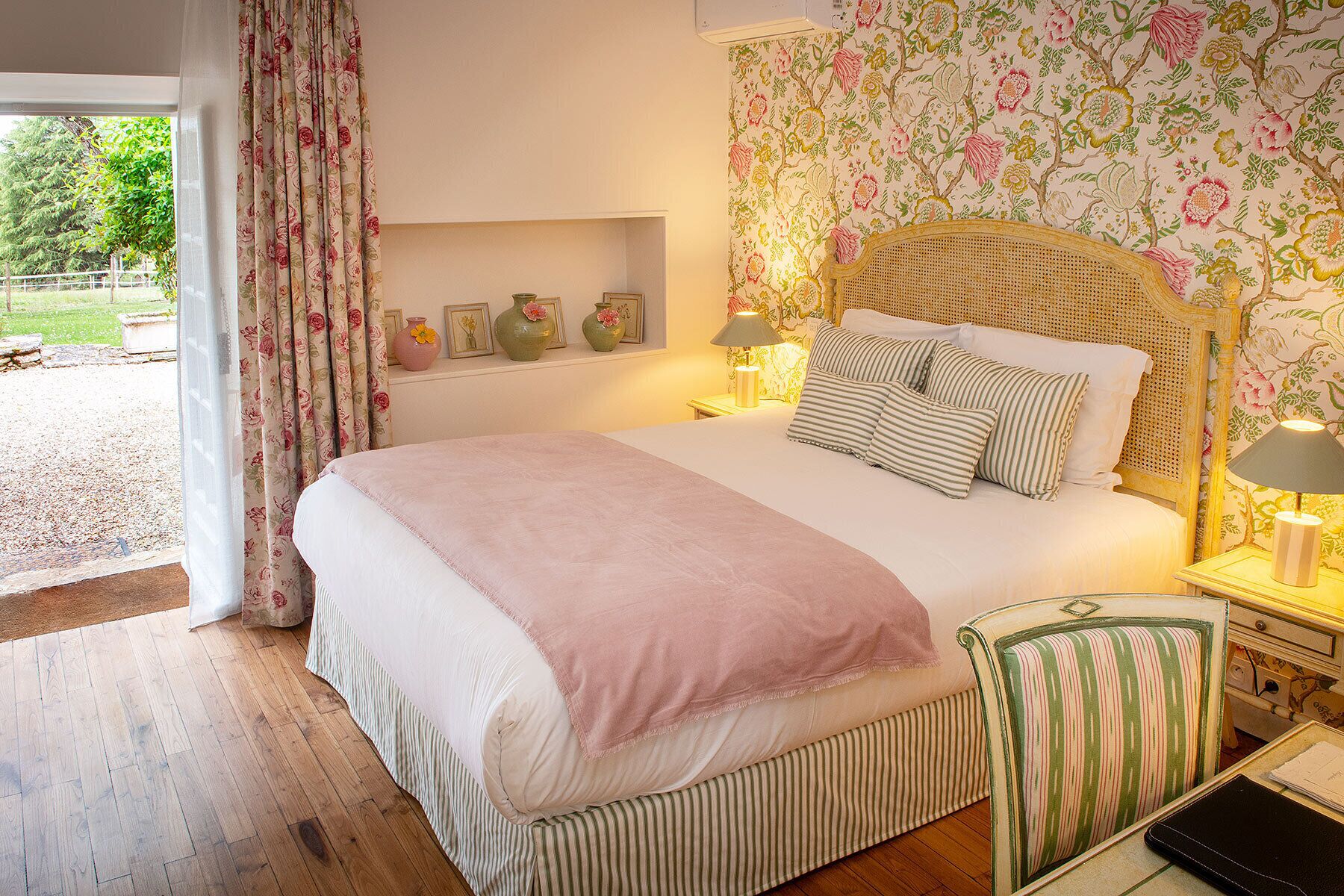 A bedroom with a bed, bedside tables, a lamp, a chair, and a window with curtains.