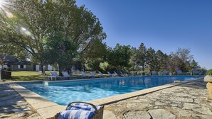 Une piscine avec des chaises longues et une terrasse en pierre.