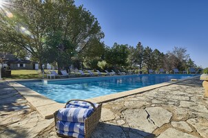 Piscina com espreguiçadeiras e deck de pedra.