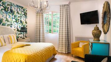 Una habitación de hotel con una cama grande, un sofá, un televisor y una ventana con cortinas.